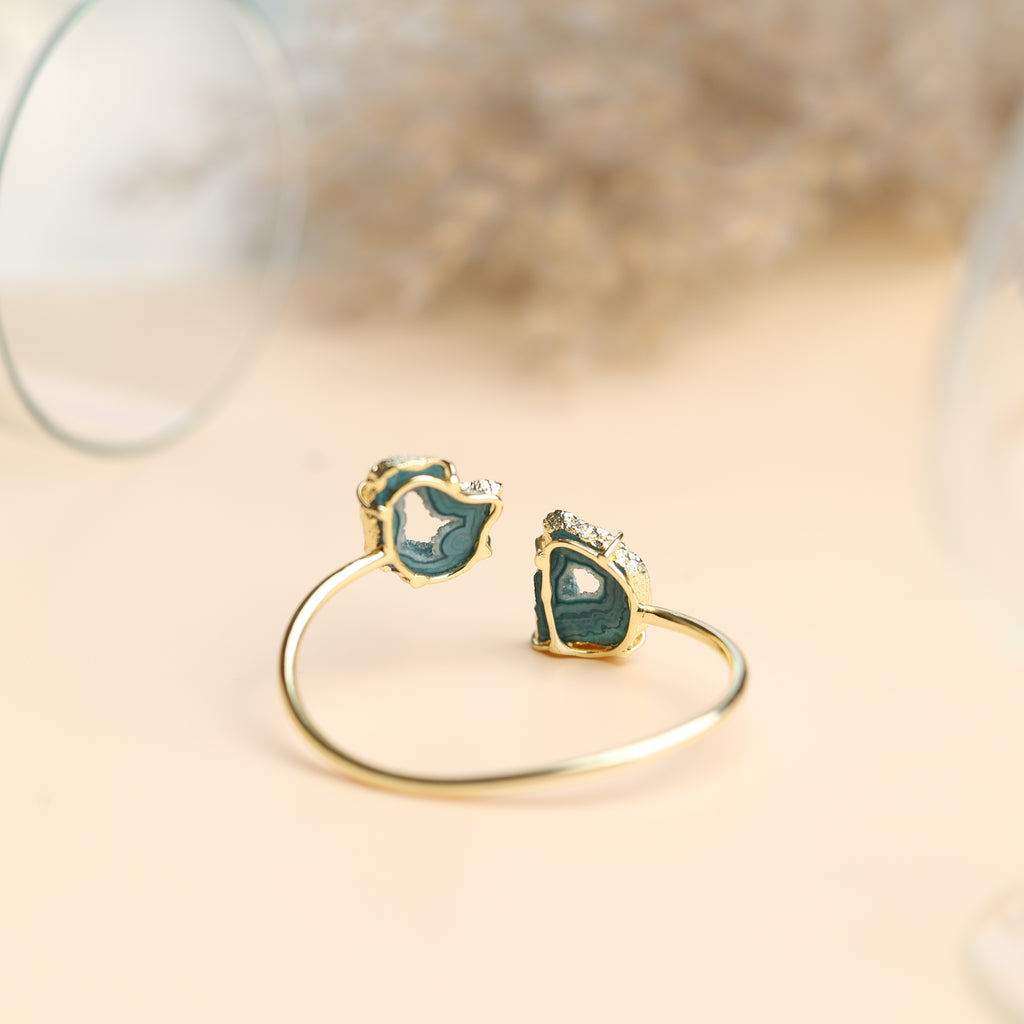 Brass cuff bracelet showcasing paired agate slices with shimmering gold borders